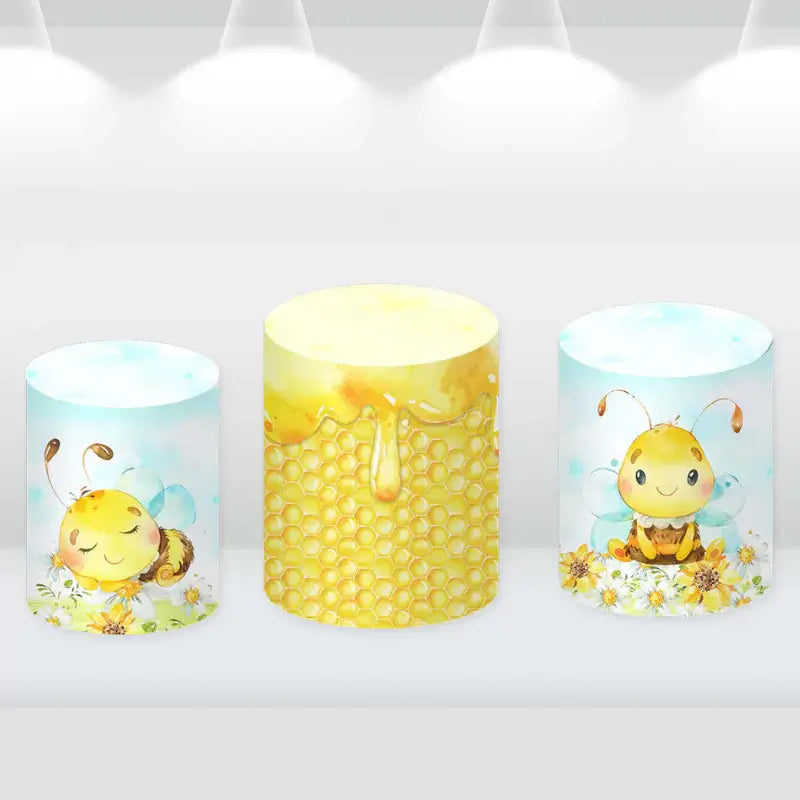 Set of three cylinder covers featuring honeycomb patterns and cute bee designs, matching the bee-themed party backdrop.