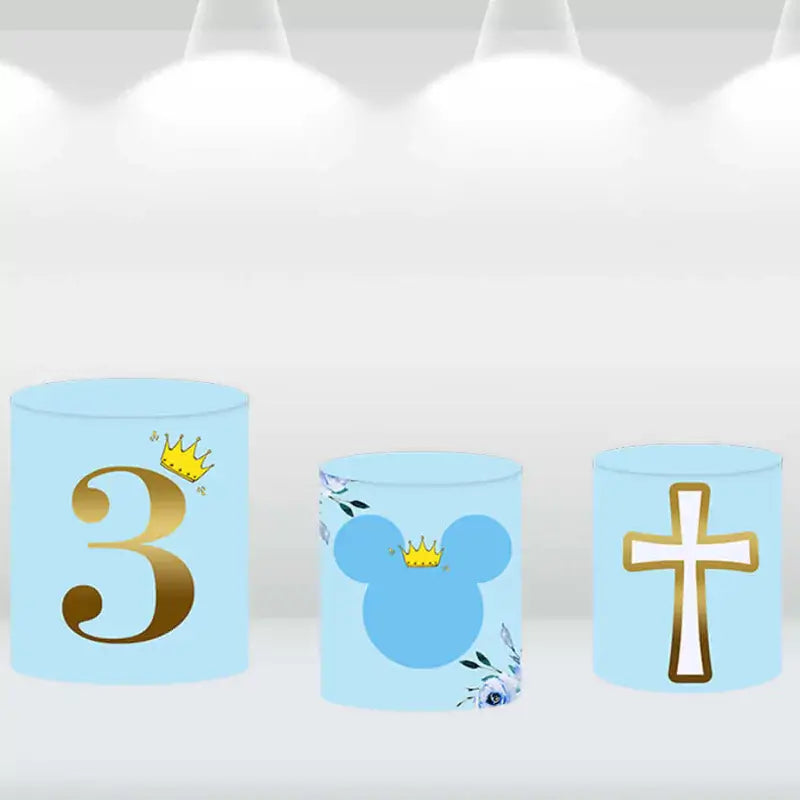 Set of three cylinder covers featuring a gold '3', a cross, and a mouse ears icon with a crown, matching the blue and gold party backdrop.