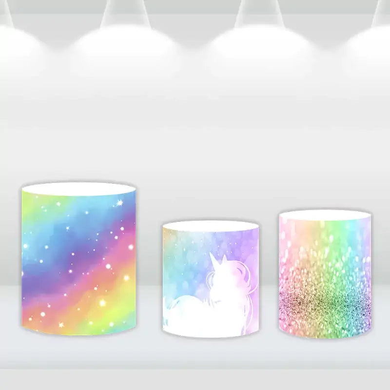 Sparkling cylinder covers with vibrant rainbow patterns, designed to complement the unicorn-themed party backdrop.