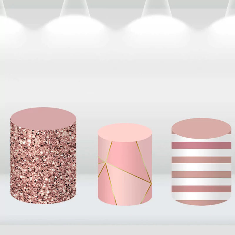 Decorative cylinder covers featuring rose gold glitter, geometric lines, and pink and white stripes, ideal for elegant event decor.