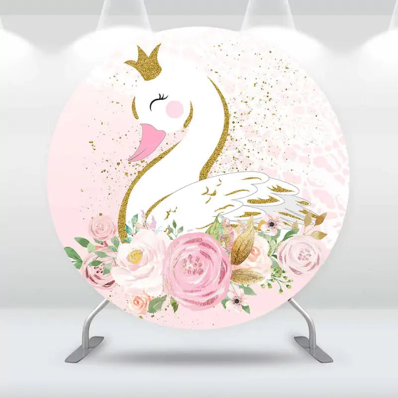 Round baby shower backdrop with a white swan wearing a golden crown, surrounded by pink and gold floral decorations.