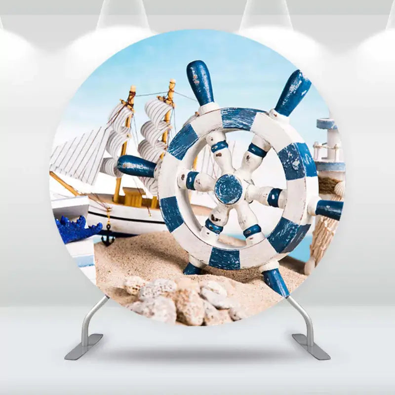 Round nautical-themed backdrop featuring a blue-and-white ship's wheel and sailboats on a beach, perfect for coastal-themed events.