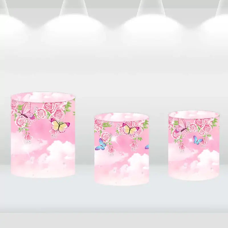 Pink cylinder covers adorned with flowers and butterflies, complementing the garden party backdrop set