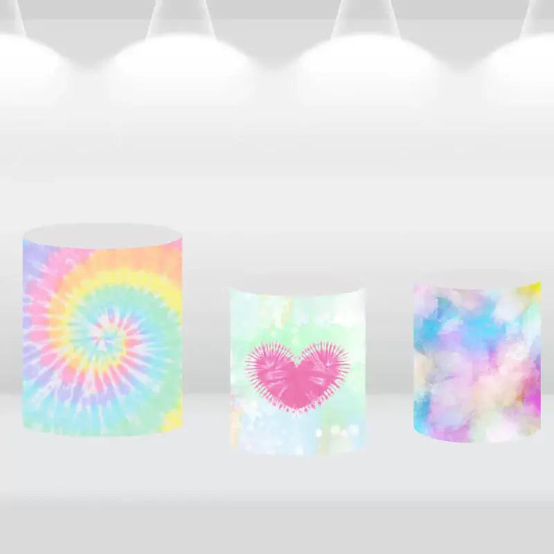 Set of three cylindrical pedestal covers featuring colorful tie-dye designs and a heart motif, perfect for complementing a tie-dye-themed event.