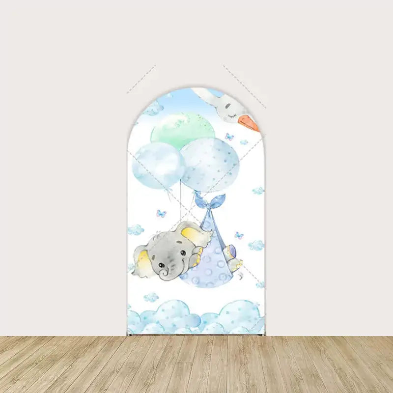 Arch panel featuring a baby boy elephant in blue sling carried by a stork—floating among blue clouds and pastel balloons.