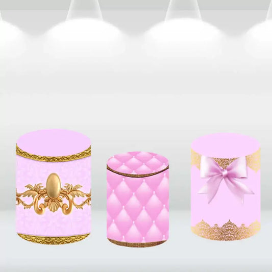 Three pink and gold decorative cylinder covers with bow, quilted, and ornate designs for event decoration