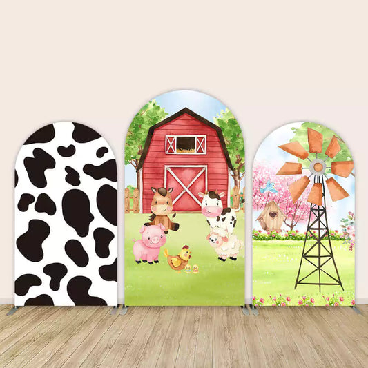 Farm-themed 3-panel arch backdrop set featuring cow print design, red barn with farm animals, and rustic windmill with flowers—great for barnyard parties.