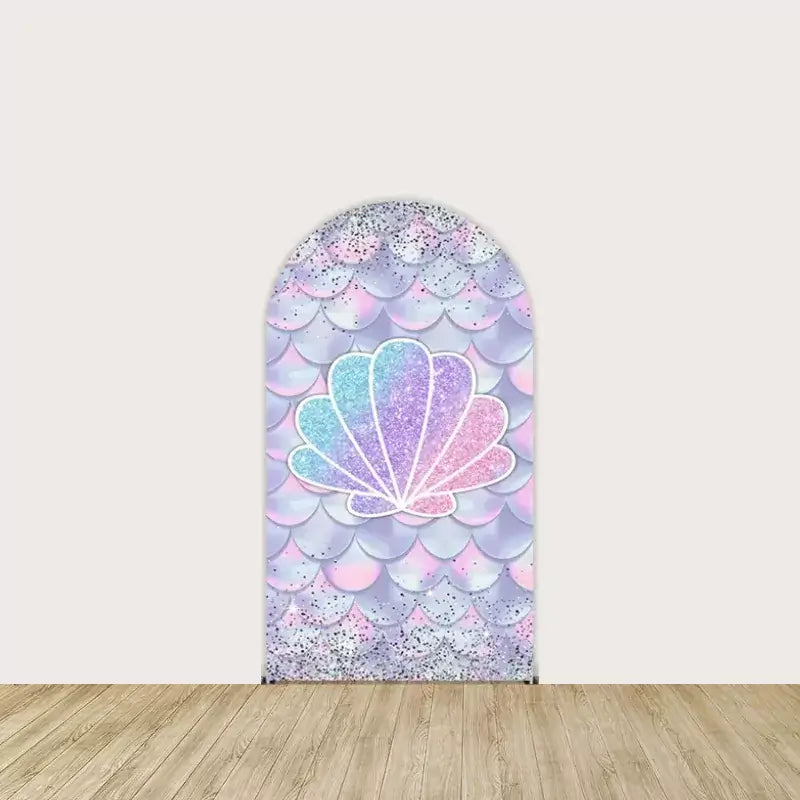 Arch panel with a large glittery pastel seashell over an iridescent scale background—magical centerpiece for mermaid-themed party setup.