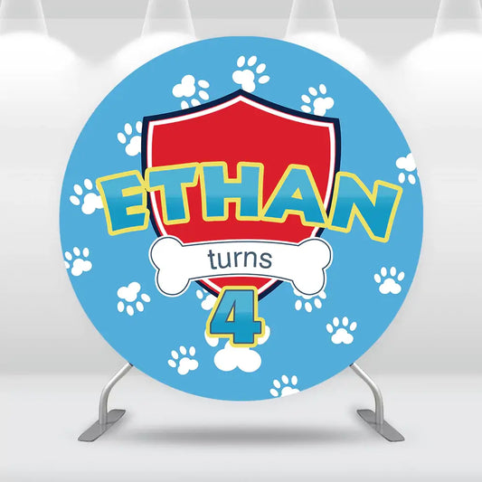 Blue birthday backdrop with white paw prints, a red shield, bone graphic, and the text 'Ethan turns 4' in bold yellow and blue letters.