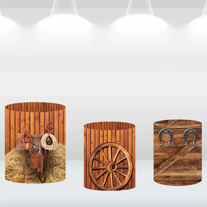 Three matching cylindrical covers with rustic designs featuring a saddle, wagon wheel, and horseshoes, ideal for a cowboy or ranch-themed backdrop.