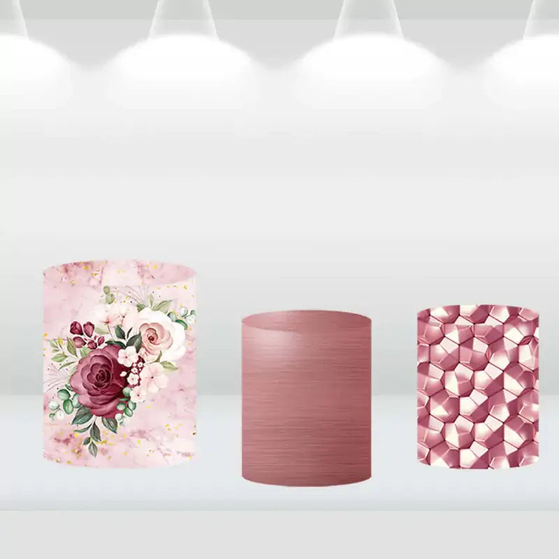Three cylinder covers featuring floral, marble, and geometric patterns in pink and burgundy, designed to complement a floral-themed round backdrop