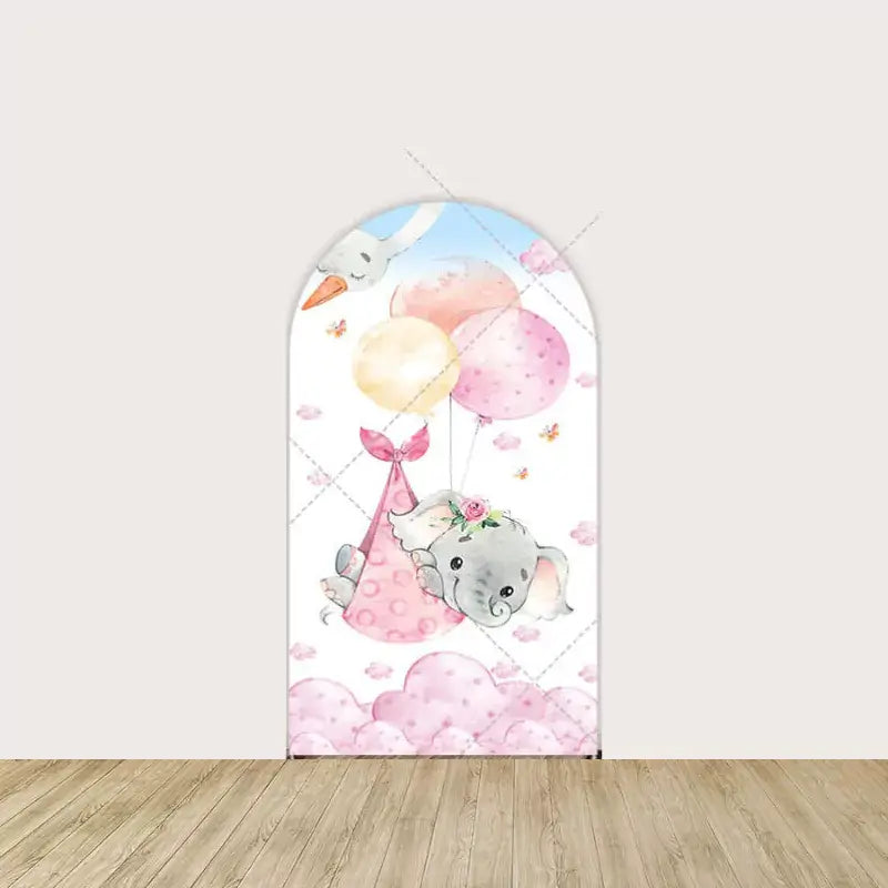 Arch panel with baby girl elephant in pink polka-dot sling carried by a stork—surrounded by pink clouds and pastel balloons.