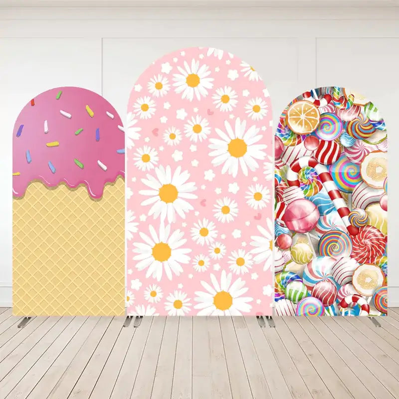 Three-panel arch backdrop set with a waffle cone and pink ice cream drip on the left, pink daisies on a floral background in the center, and rainbow candies on the right.
