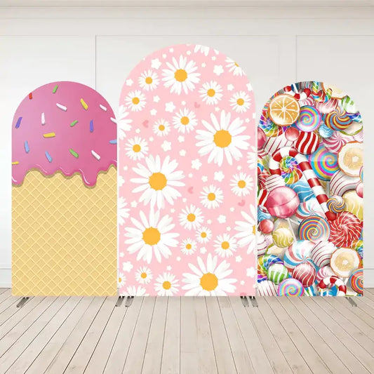 Three-panel arch backdrop set with a waffle cone and pink ice cream drip on the left, pink daisies on a floral background in the center, and rainbow candies on the right.