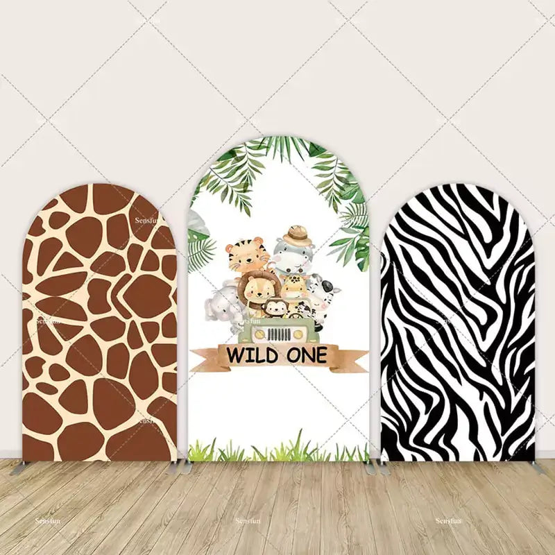 Set of arched backdrops with giraffe and zebra prints and a safari-themed “Wild One” animal design