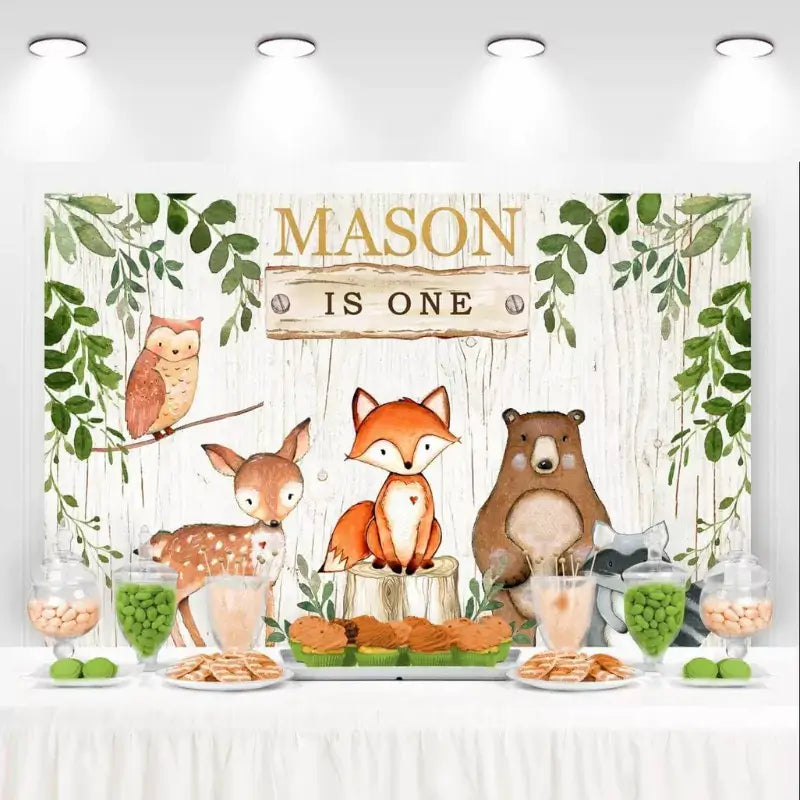 Rustic woodland animals birthday backdrop with owl, fox, deer, bear, and greenery for Mason’s first birthday.