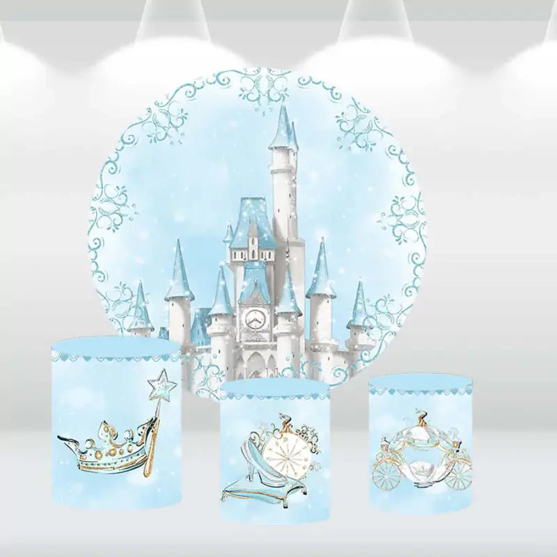 Fairy tale castle party decor set with a snowy backdrop and cylinder covers adorned with a glass slipper, royal carriage, and crown.