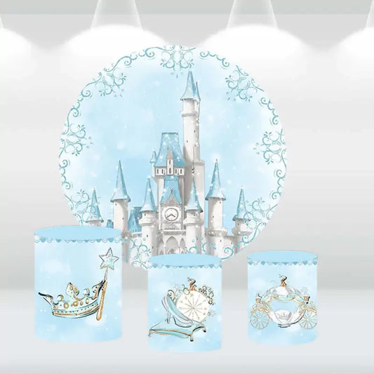 Fairy tale castle party decor set with a snowy backdrop and cylinder covers adorned with a glass slipper, royal carriage, and crown.
