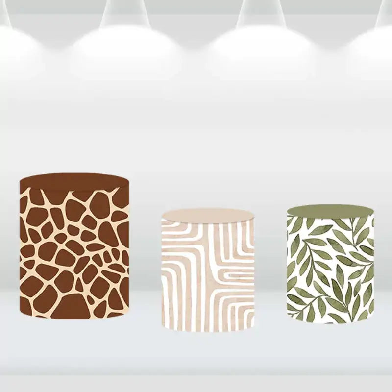 Cylinder covers with safari-inspired designs: giraffe print, zebra stripes, and leafy patterns, complementing the safari backdrop.