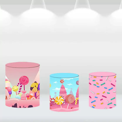 Pink and blue cylinder covers featuring candy designs and sprinkles, part of a candy-themed backdrop set.