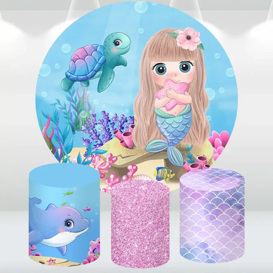 Mermaid and sea life party decor set featuring a round underwater backdrop and cylinder covers with dolphin, glitter, and scale designs.