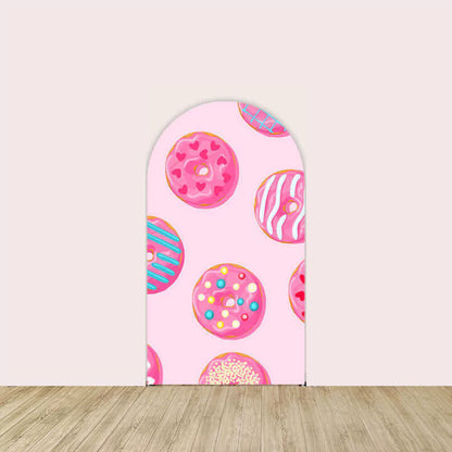 Left arch backdrop with a pink background featuring colorful donut illustrations decorated with sprinkles and frosting.