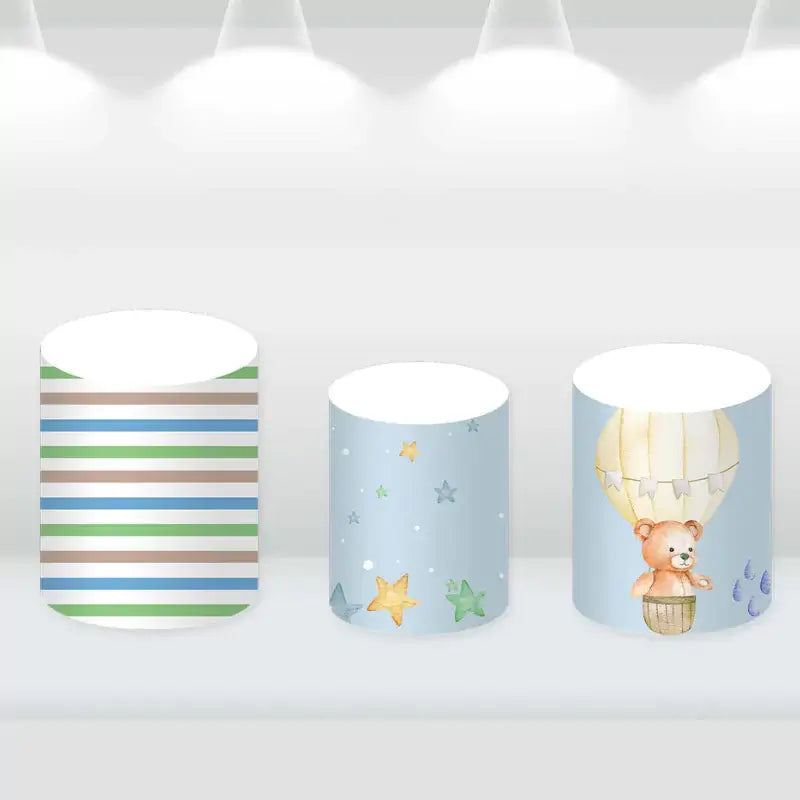 Whimsical cylinder covers featuring stars, stripes, and a teddy bear in a hot air balloon.