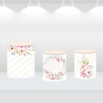 Floral-themed cylinder covers with watercolor flower patterns and rustic wood accents, complementing the party backdrop.