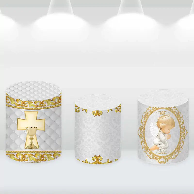 Gold and white cylinder covers with religious motifs, complementing the elegant baptism backdrop with a praying angel design.