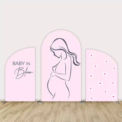 Three-piece pink baby shower arch backdrop featuring a line-art pregnant woman, “Baby in Bloom” text, and daisy flower accents in soft pastel tones.