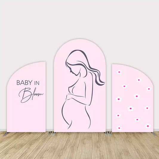 Three-piece pink baby shower arch backdrop featuring a line-art pregnant woman, “Baby in Bloom” text, and daisy flower accents in soft pastel tones.