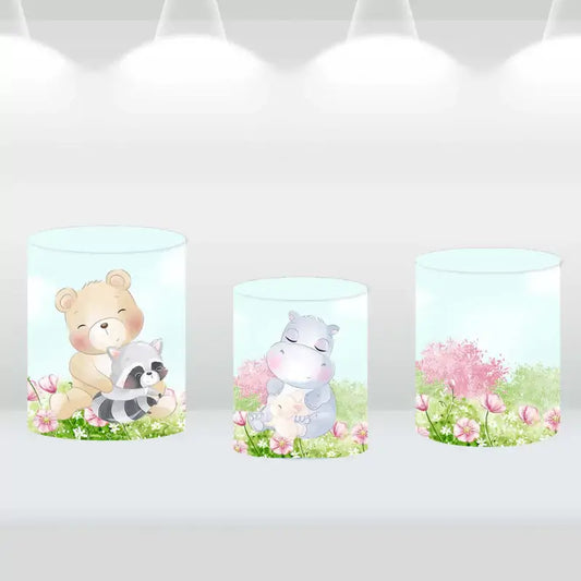 Three animal-themed backdrop cylinder covers with bear, raccoon, and hippo designs in floral background
