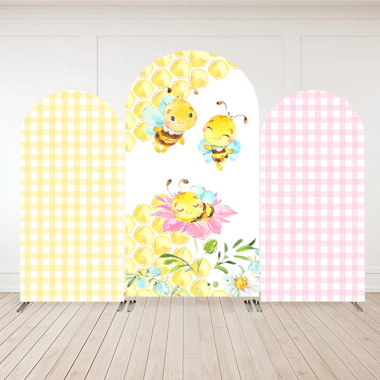 Three-panel arch backdrop featuring watercolor bees on honeycomb with flowers, yellow gingham on the left, and pink gingham on the right.