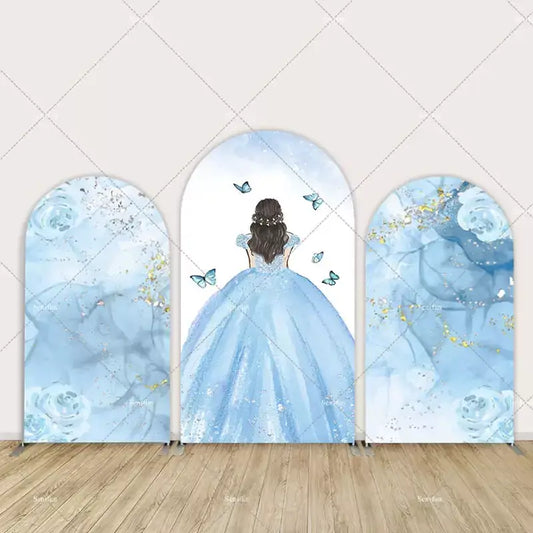 Three-panel arch backdrop set featuring a girl in a sparkling blue ball gown surrounded by butterflies, watercolor roses, and glittering blue textures.