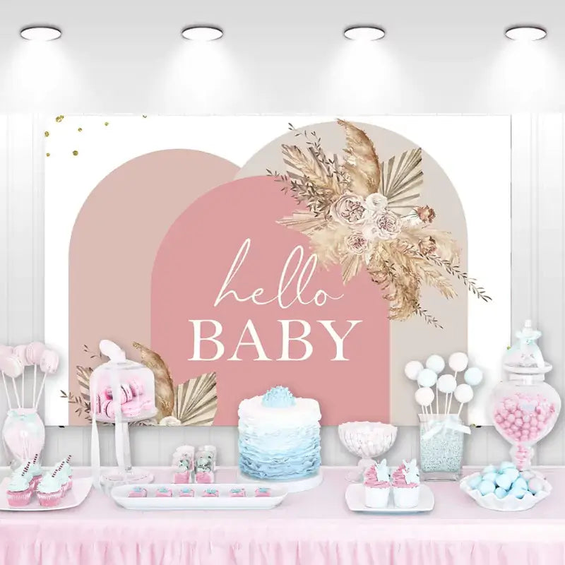 Boho-style baby shower backdrop with blush arches and dried floral arrangement reading 'Hello Baby'.