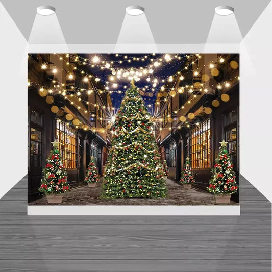 Christmas street scene backdrop with a large decorated tree, glowing string lights overhead, and shopfronts illuminated for a festive evening celebration