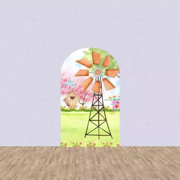 Backdrop with a windmill and birdhouse in a field, surrounded by pink flowers and greenery, creating a rustic countryside feel.