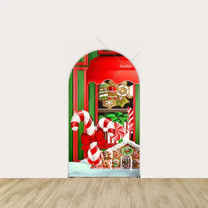 Left side of candy shop backdrop with gingerbread house, candy canes with bows, and holiday sweets in a festive red and green display.