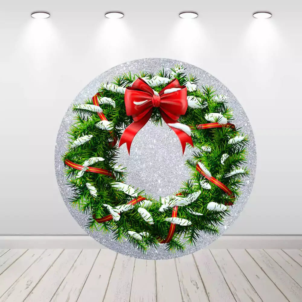 Round backdrop with a snowy Christmas wreath, decorated with a red bow and ribbons, set against a silver background for a festive holiday touch.