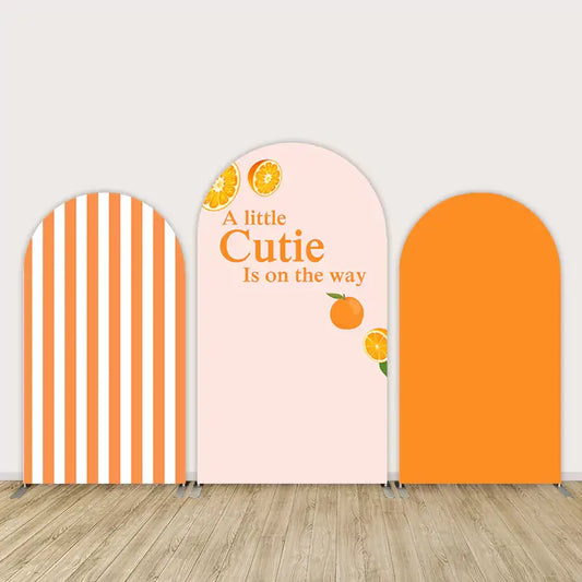 Citrus-themed baby shower backdrop set with “A Little Cutie Is on the Way” text and orange designs