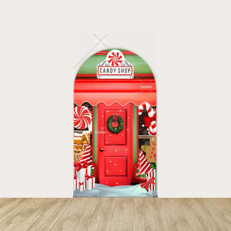 Red door with wreath, peppermint swirls, and gingerbread house decorations.
