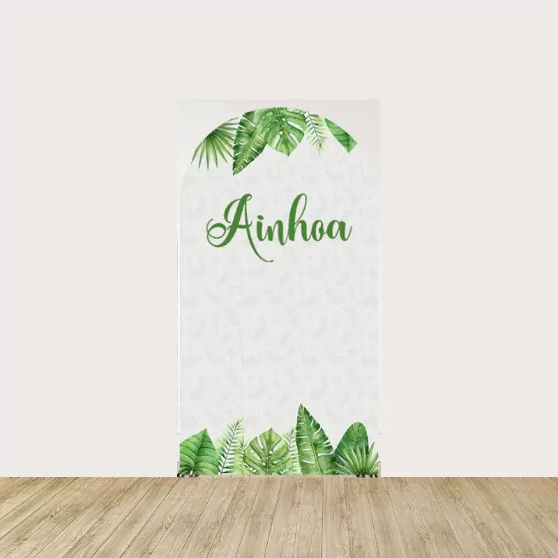 Arch arch panel with custom name “Ainhoa” in green script, pale botanical print, and tropical palm leaves at the base—elegant centerpiece panel.