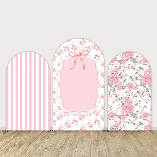 Three-piece arched backdrop set featuring a pink and white striped cover, a floral frame with a pink bow centerpiece, and a pink rose design, perfect for baby showers or elegant events.