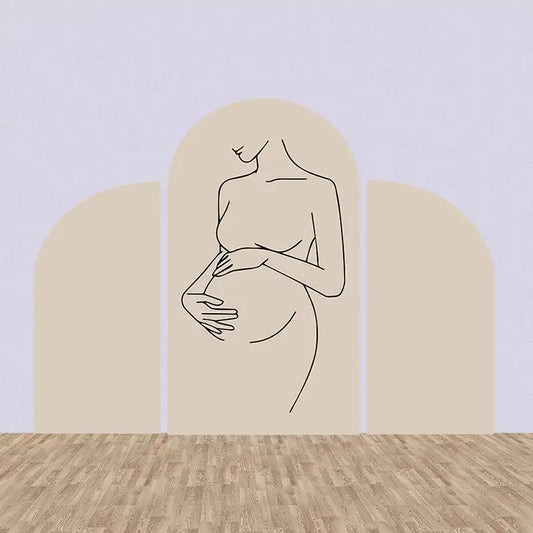 Three-piece arch backdrop set with center panel featuring a minimalist line art silhouette of a pregnant woman, flanked by nude solid arches.