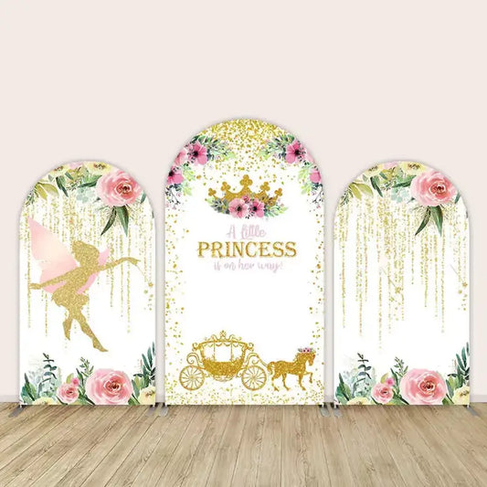 Three-panel princess baby shower arch backdrop featuring a gold fairy silhouette on one side, “A little princess is on her way” with a crown and carriage in the center, and floral drapes of gold glitter on the third arch.