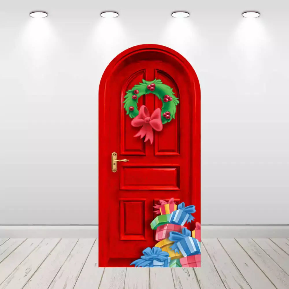 Red door backdrop decorated with a Christmas wreath with a pink bow, surrounded by colorful wrapped gifts at the bottom, ideal for holiday parties.