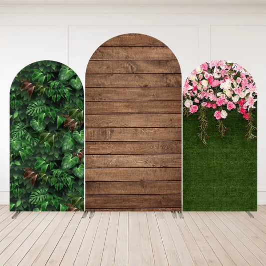 Three-panel arch backdrop featuring tropical green leaves, rustic wood planks, and green grass with cascading pink and white roses.