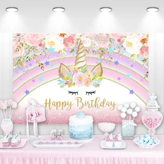 Unicorn birthday party backdrop featuring a pink and gold theme with floral decorations and a unicorn design, ideal for a magical celebration.