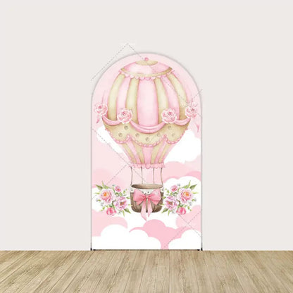 Center panel with ornate pink hot air balloon trimmed in roses and ribbons—set against a sky of white and blush pink clouds.